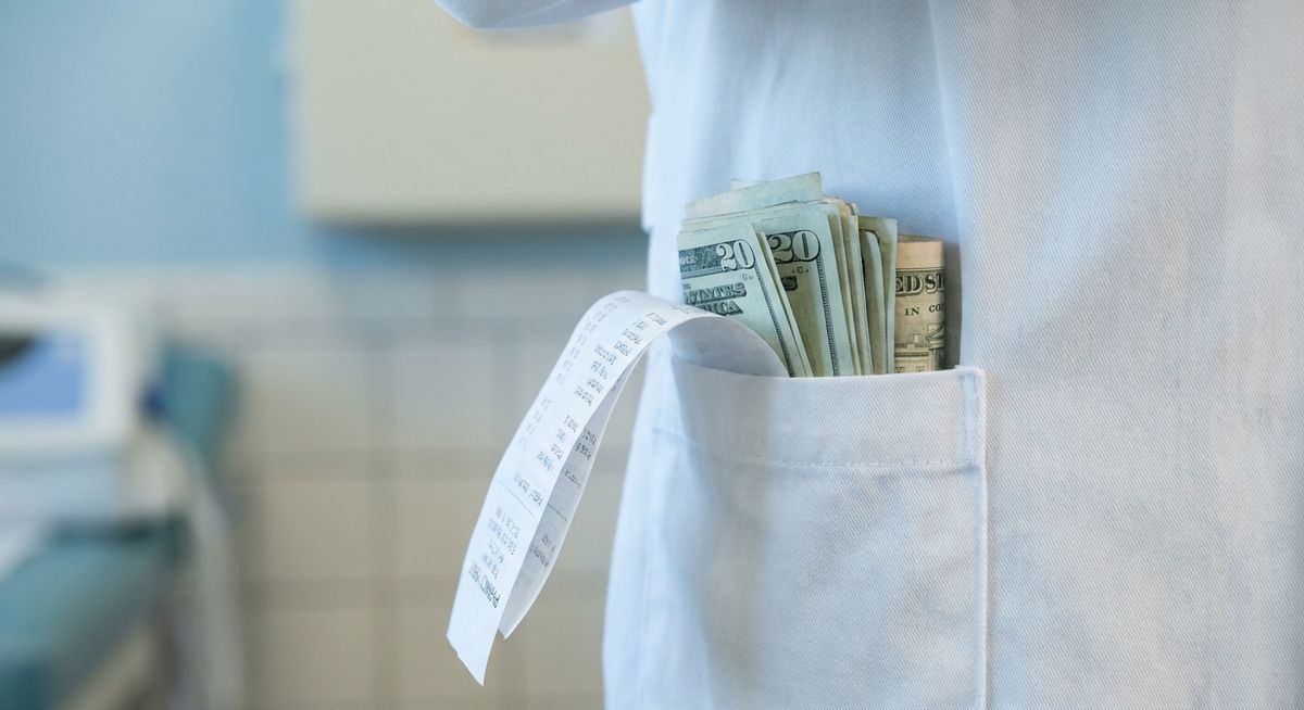 Close-up of a white doctor's coat pocket overflowing with rolled cash and a folded receipt